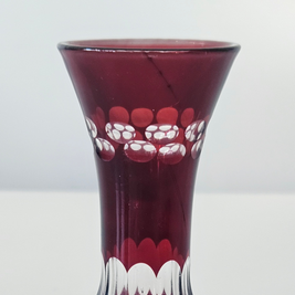 Red glass vase with white floral patterns on a white background
