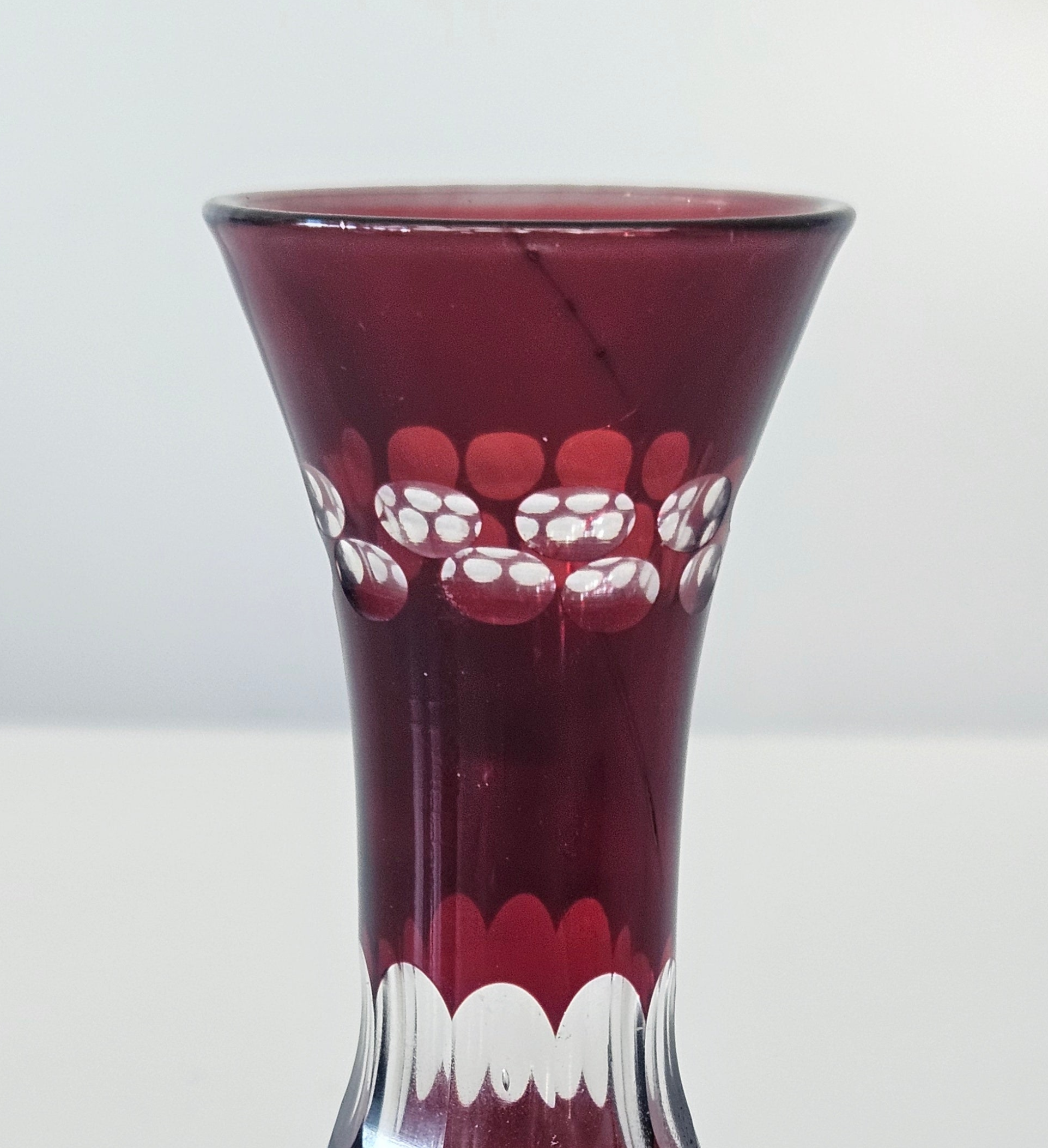 Red glass vase with white floral patterns on a white background