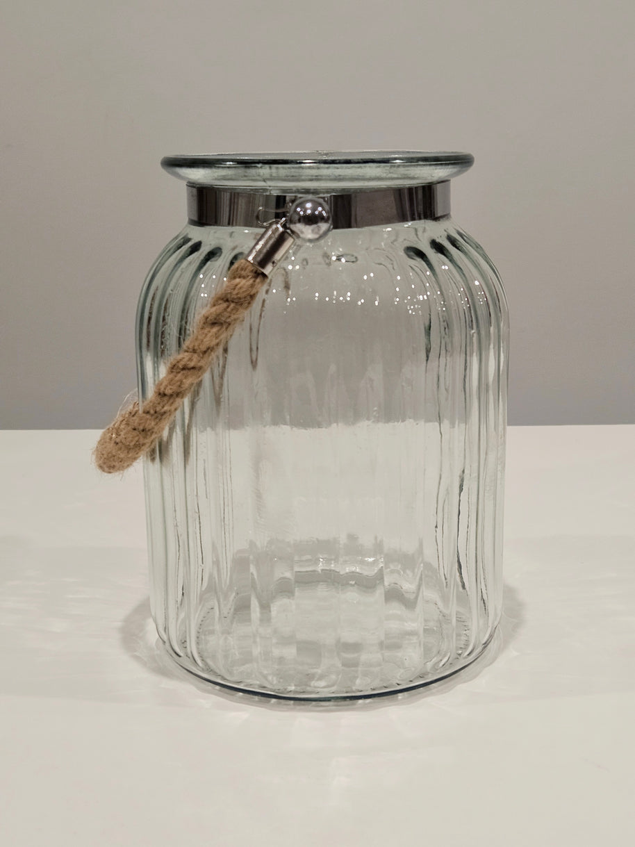 Clear glass jar with a silver lip and rope handle on a white surface.