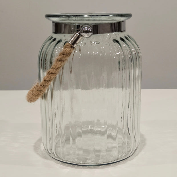 Clear glass jar with a silver lip and rope handle on a white surface.
