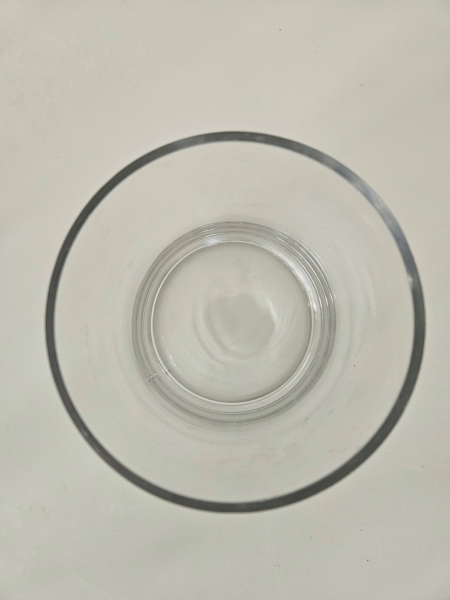 Top down view of a clear cylindrical glass vase on a white background