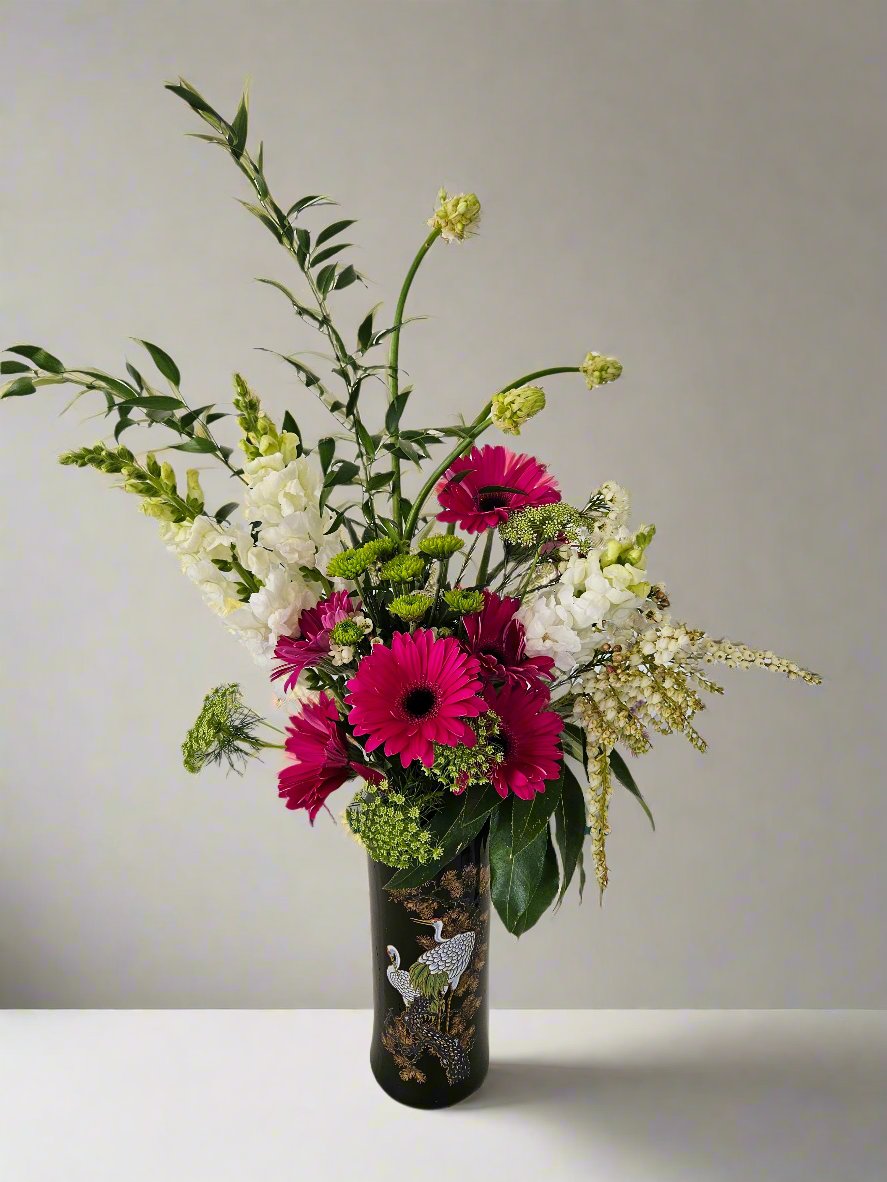Bouquet of flowers in a black decorative vase with white stalks on a plain background