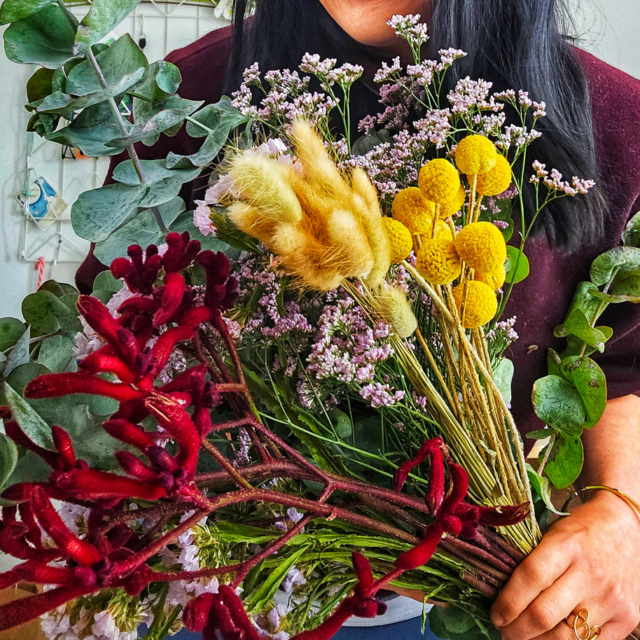 Person holding a bouquet of flowers with greenery and Australian native flowers