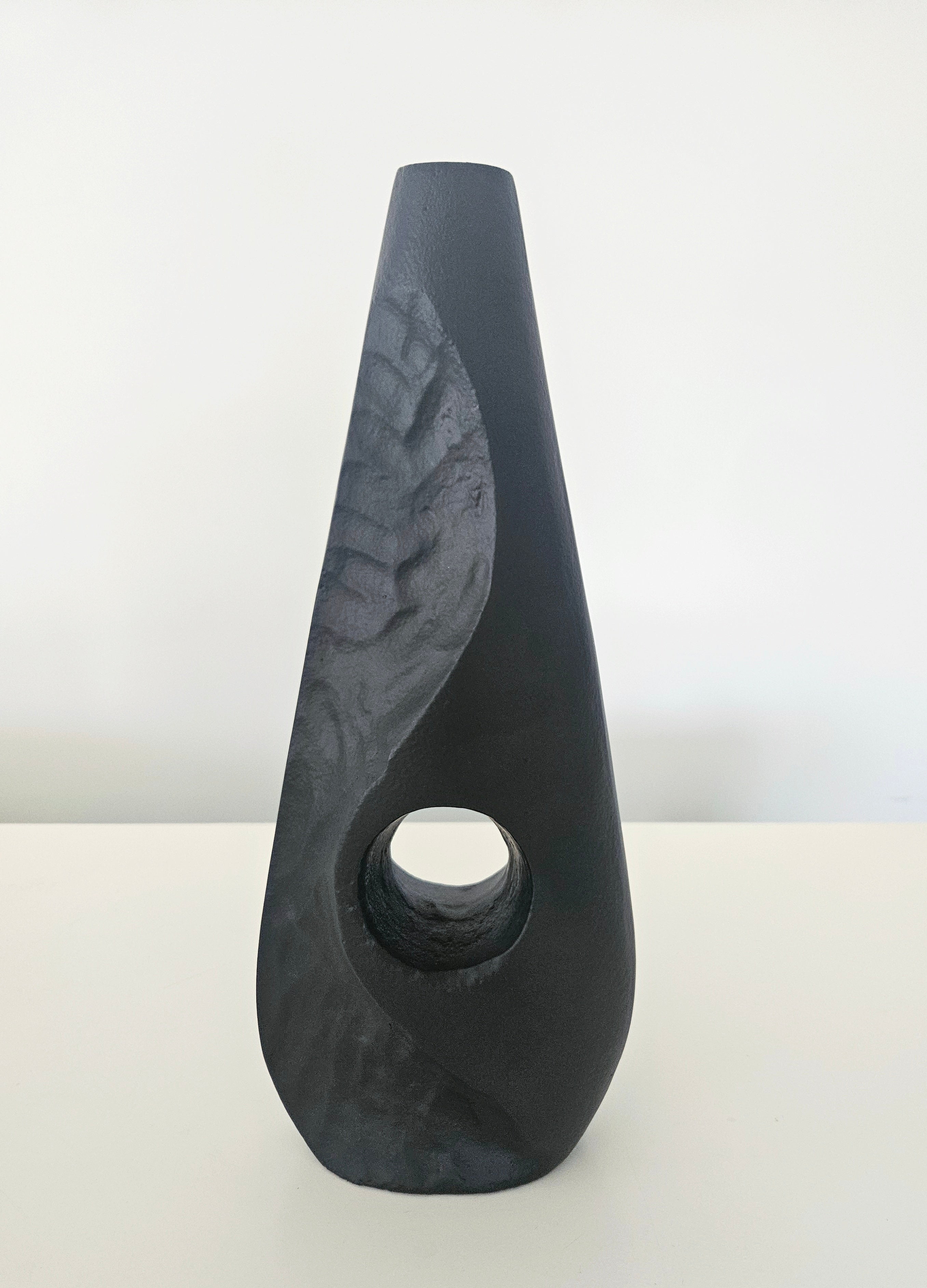 Black stone vase on a white surface with a light gray background