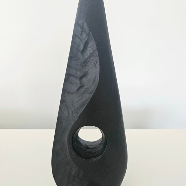 Black stone vase on a white surface with a light gray background