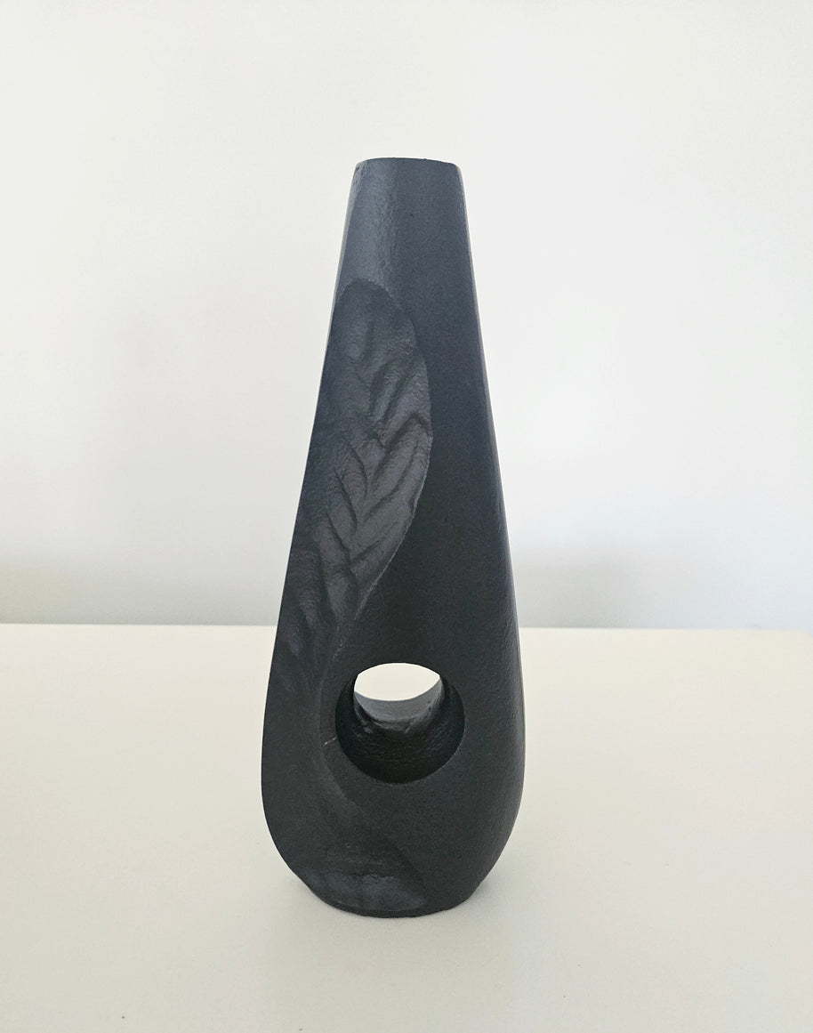 Black ceramic vase with a textured surface on a white background