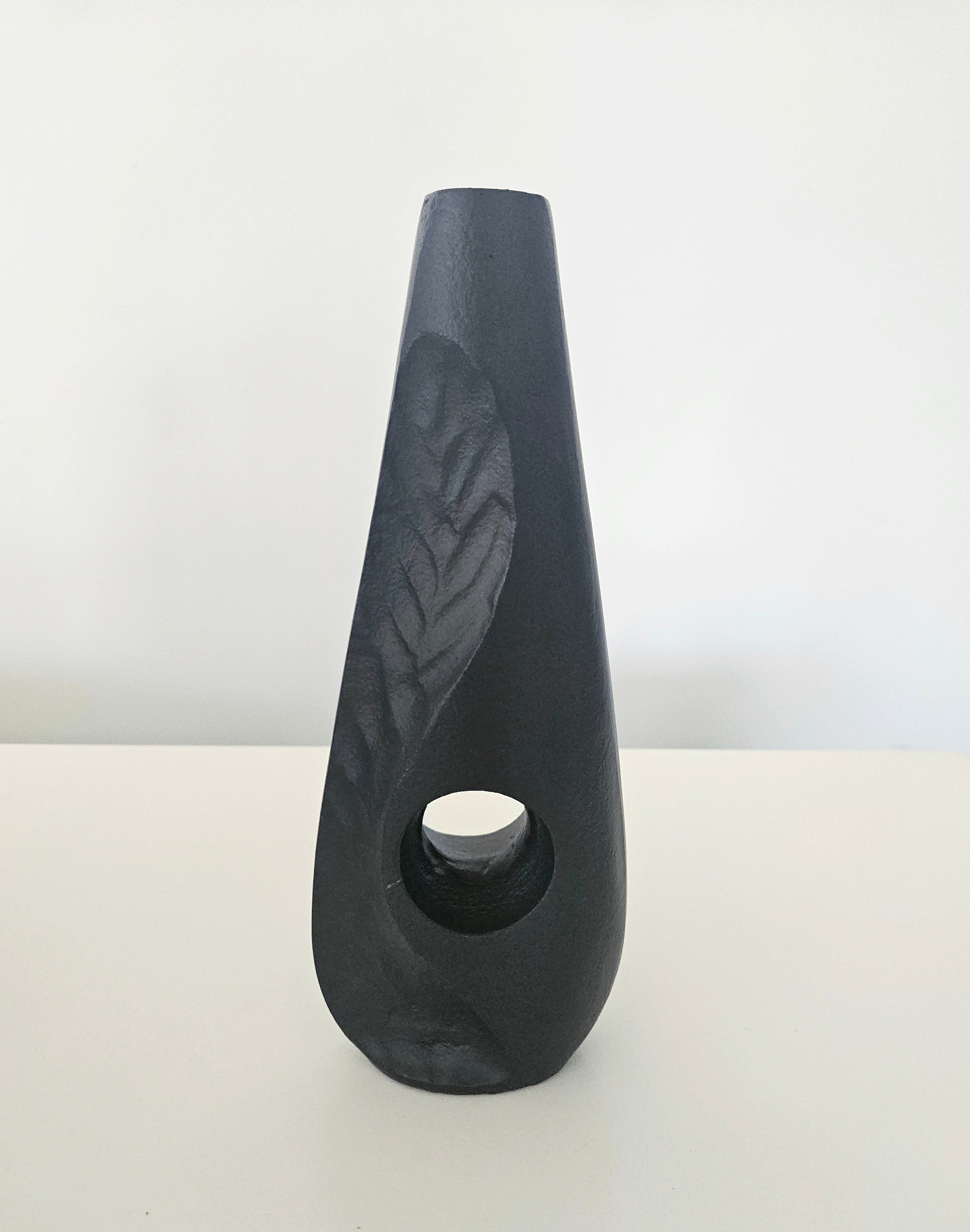 Black ceramic vase with a textured surface on a white background