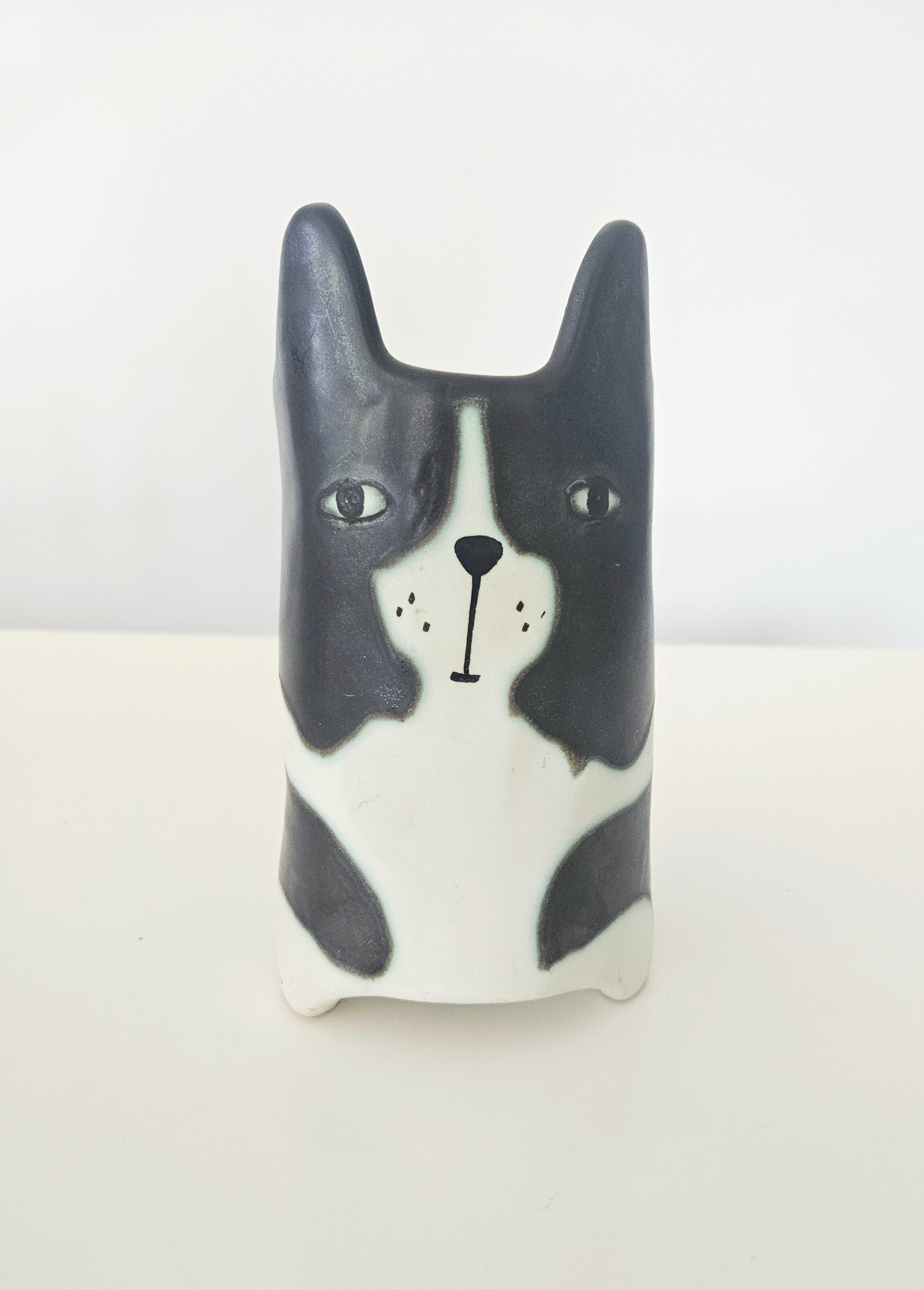 Ceramic dog-shaped pot with black and white design on a light background