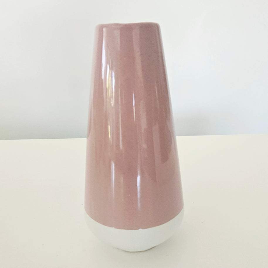 Pink and white ceramic vase on a white surface with a white background