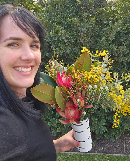 Person holding a bouquet of flowers with greenery in the background