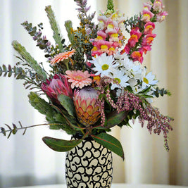 Bouquet of flowers in a decorative black and white vase on a white surface with a blurred background