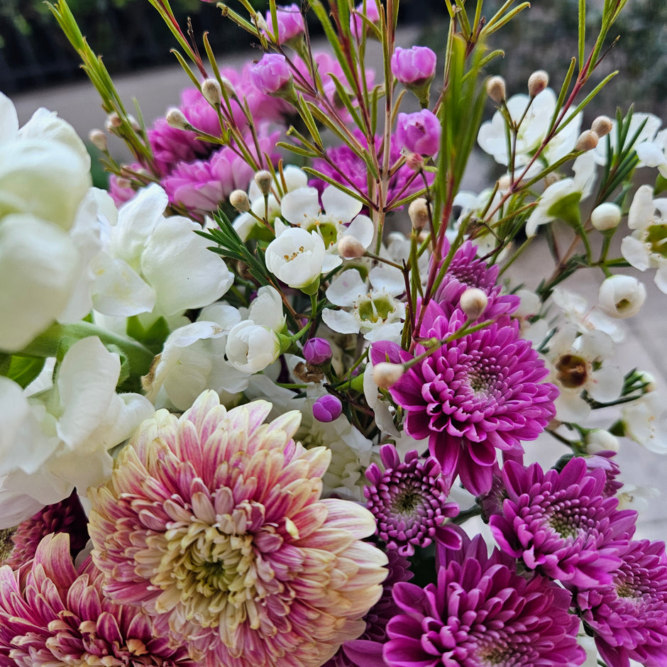Bouquet of purple, white, and pink flowers with greenery.