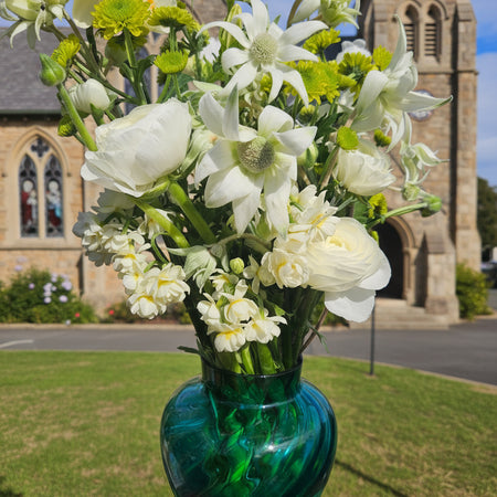 Person holding a vase of flowers in front of a church