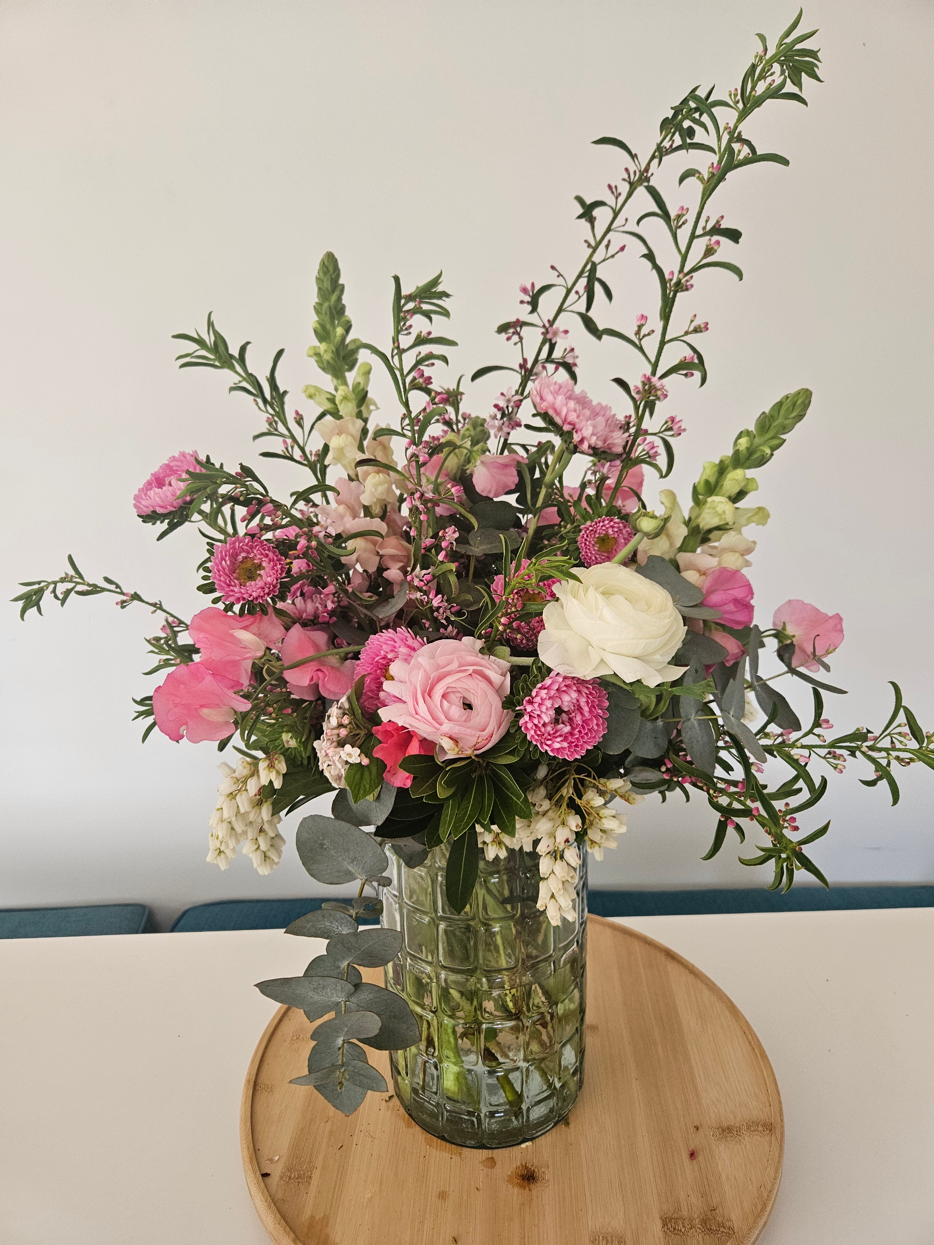 Bouquet of pink and white flowers in a clear vase on a light background