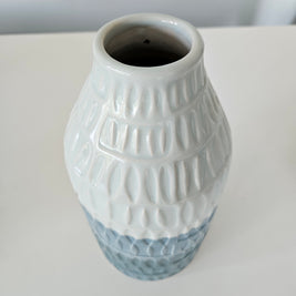 Ceramic blue and white striped vase with textured design on a white background