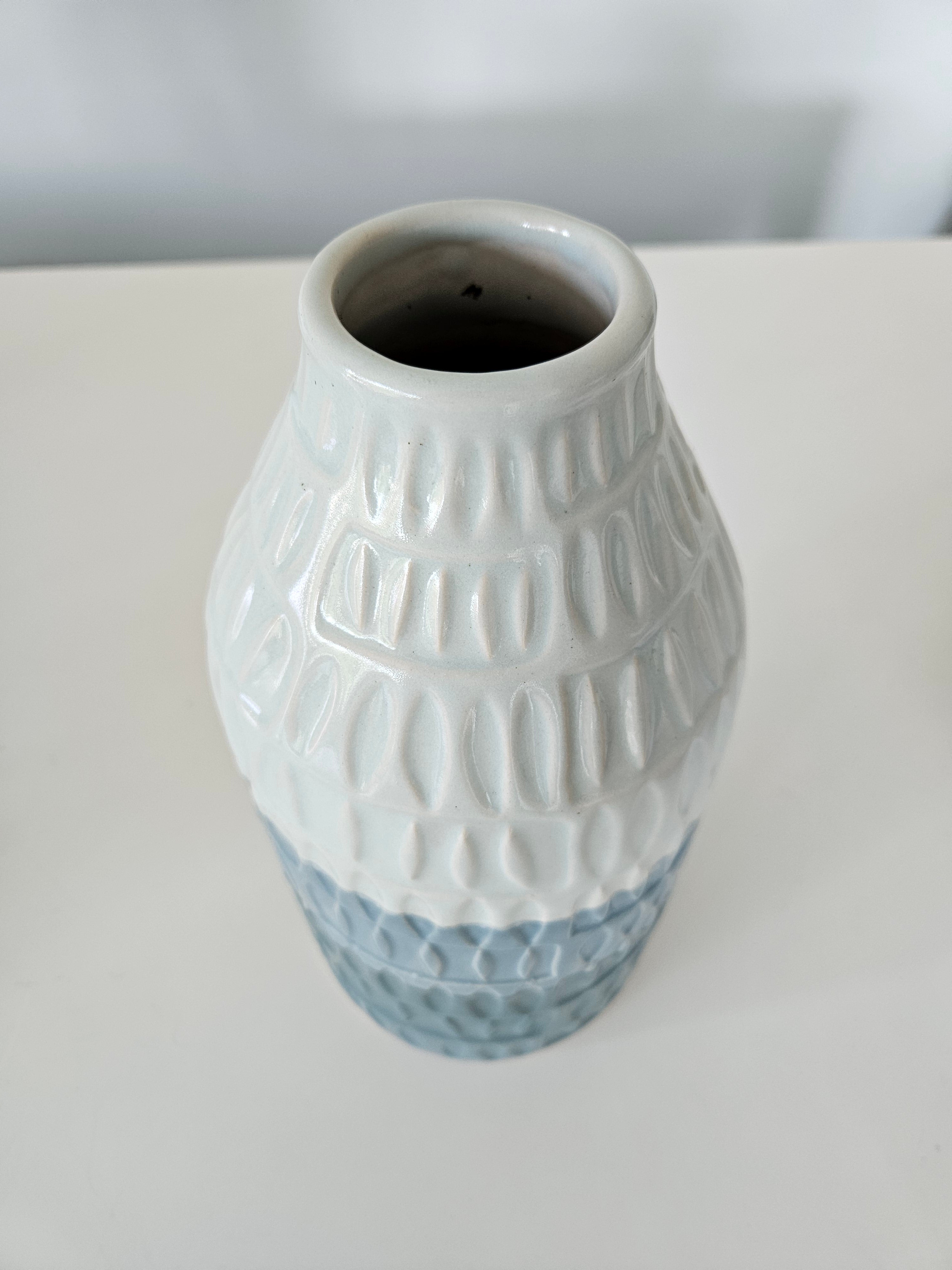 Ceramic blue and white striped vase with textured design on a white background