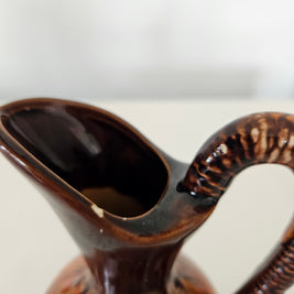 Close up of a chip on the rim of a brown pitcher vase