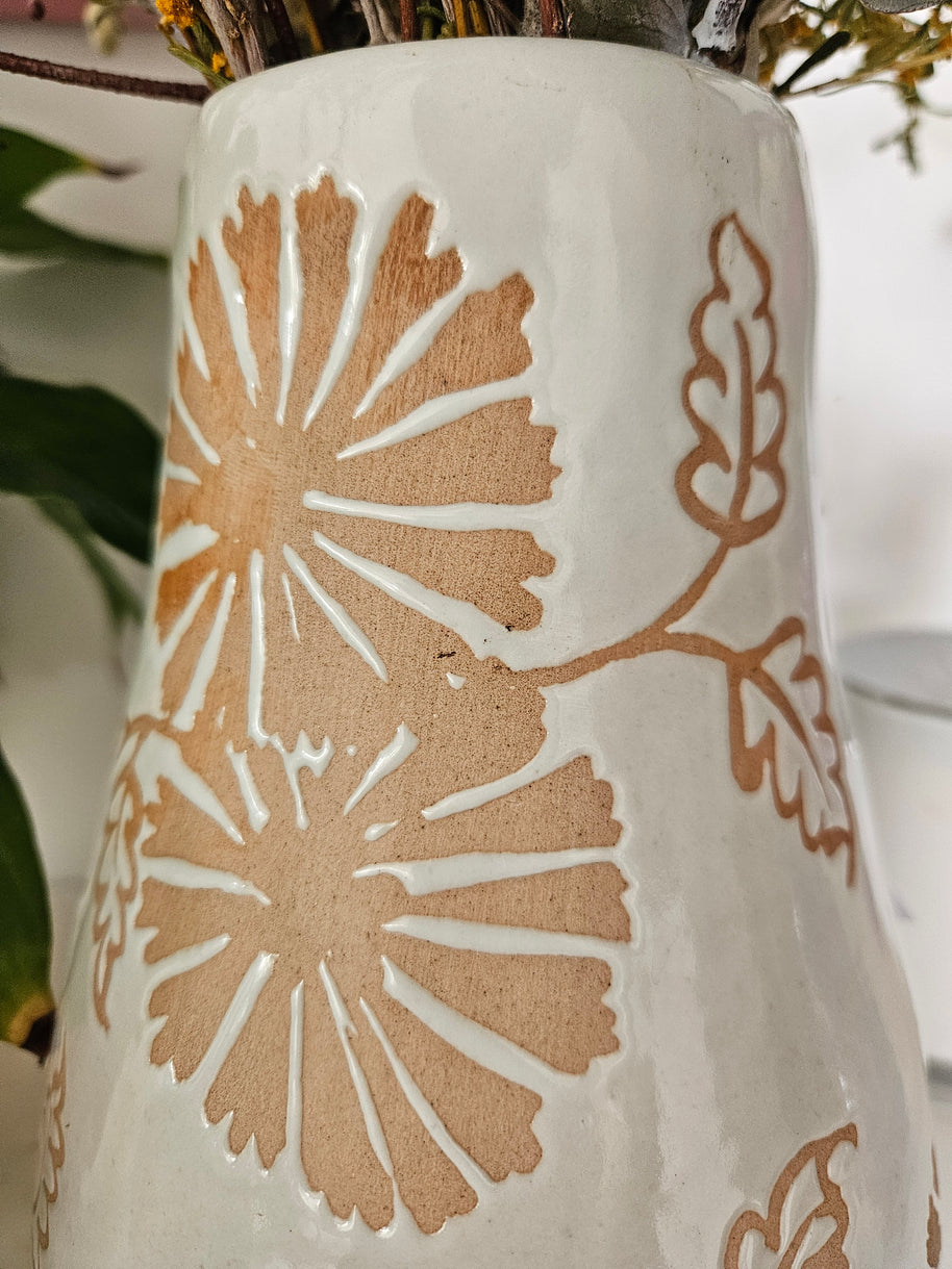 Close up of marks on a ceramic vase with floral patterns on a white background