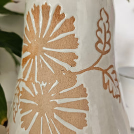 Close up of marks on a ceramic vase with floral patterns on a white background