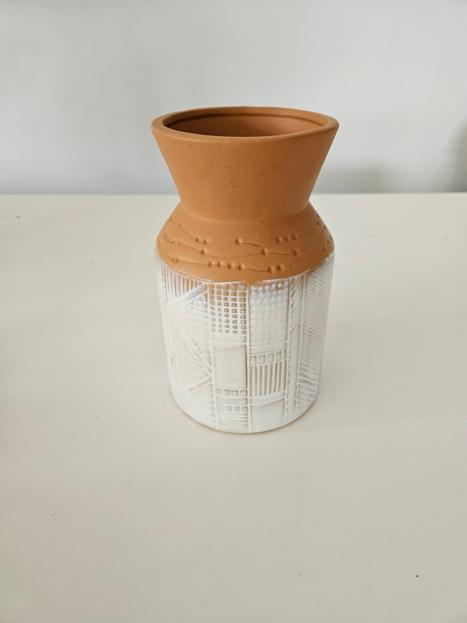 Terracotta pot with a white painted base on a white background