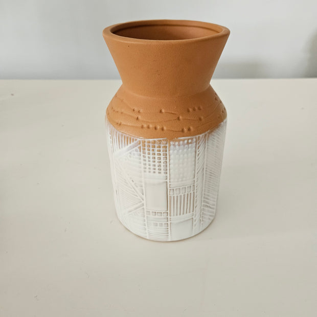Terracotta pot with a white painted base on a white background