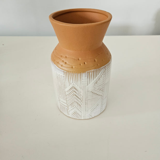 Decorative vase with terracotta base and white textured top on a light background