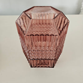 Decorative pink glass vase with textured design on a white background