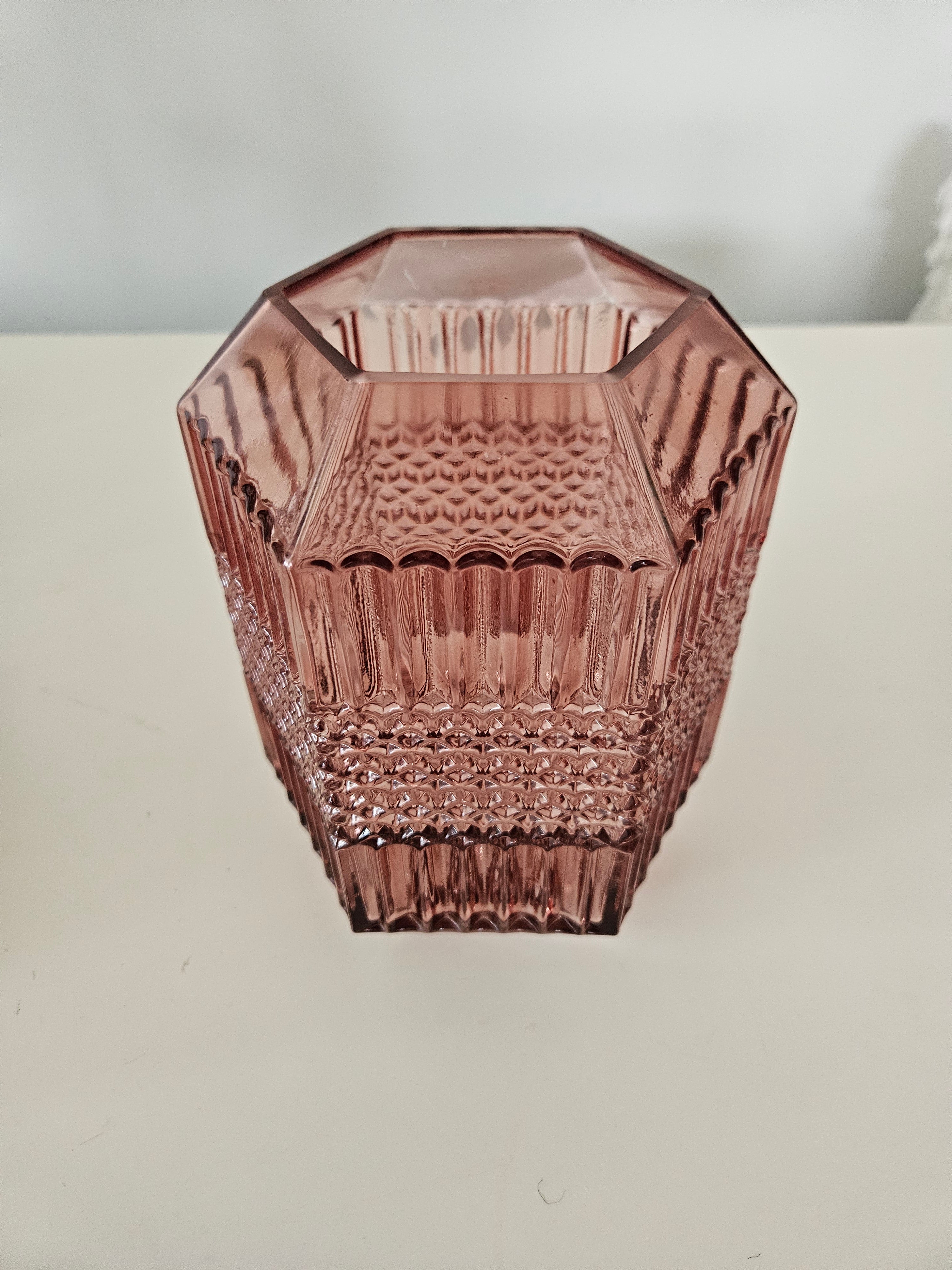 Decorative pink glass vase with textured design on a white background