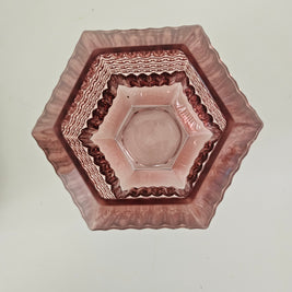 Top down view of a hexagonal glass vase with decorative rim on a plain background