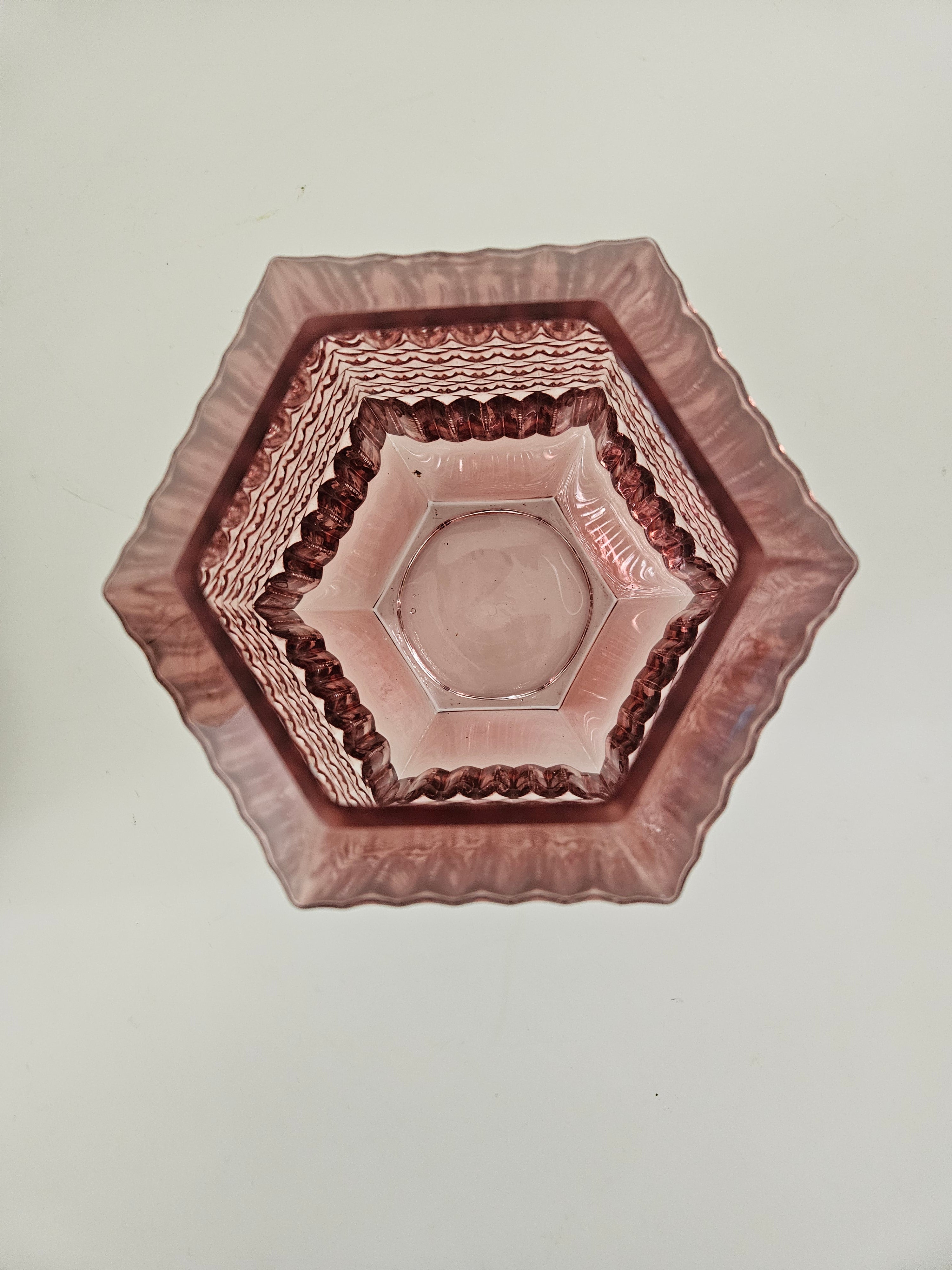 Top down view of a hexagonal glass vase with decorative rim on a plain background