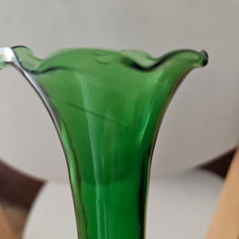 Close-up of a green glass vase with a blurred background