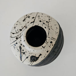 Top down view of a ceramic vase with black splatter design on a white background