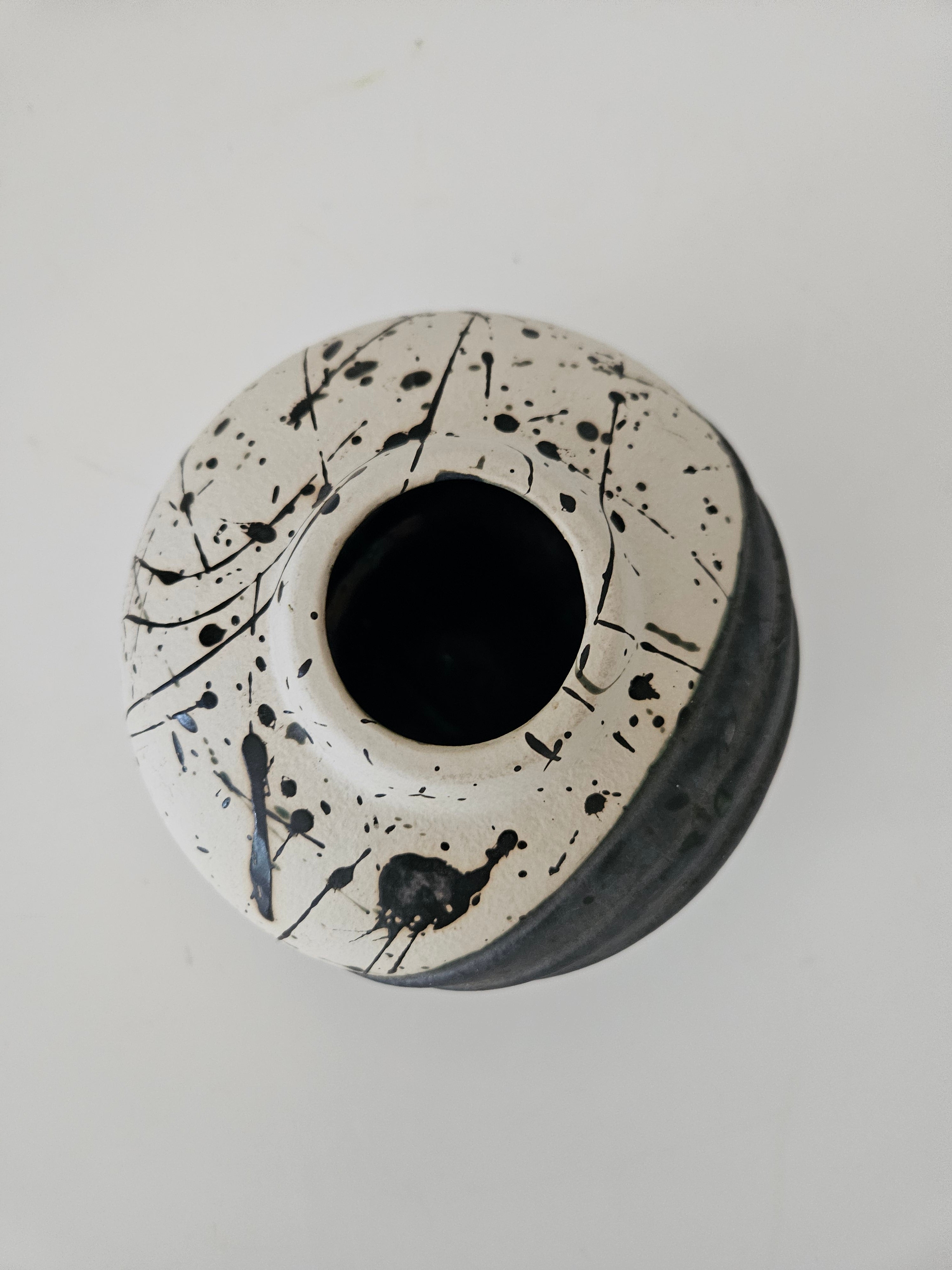 Top down view of a ceramic vase with black splatter design on a white background