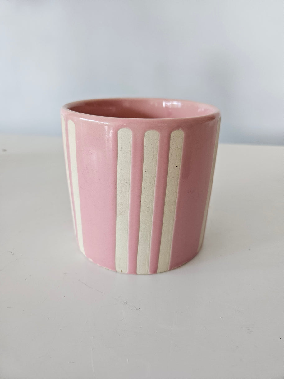 Pink and white ceramic striped pot on a white background