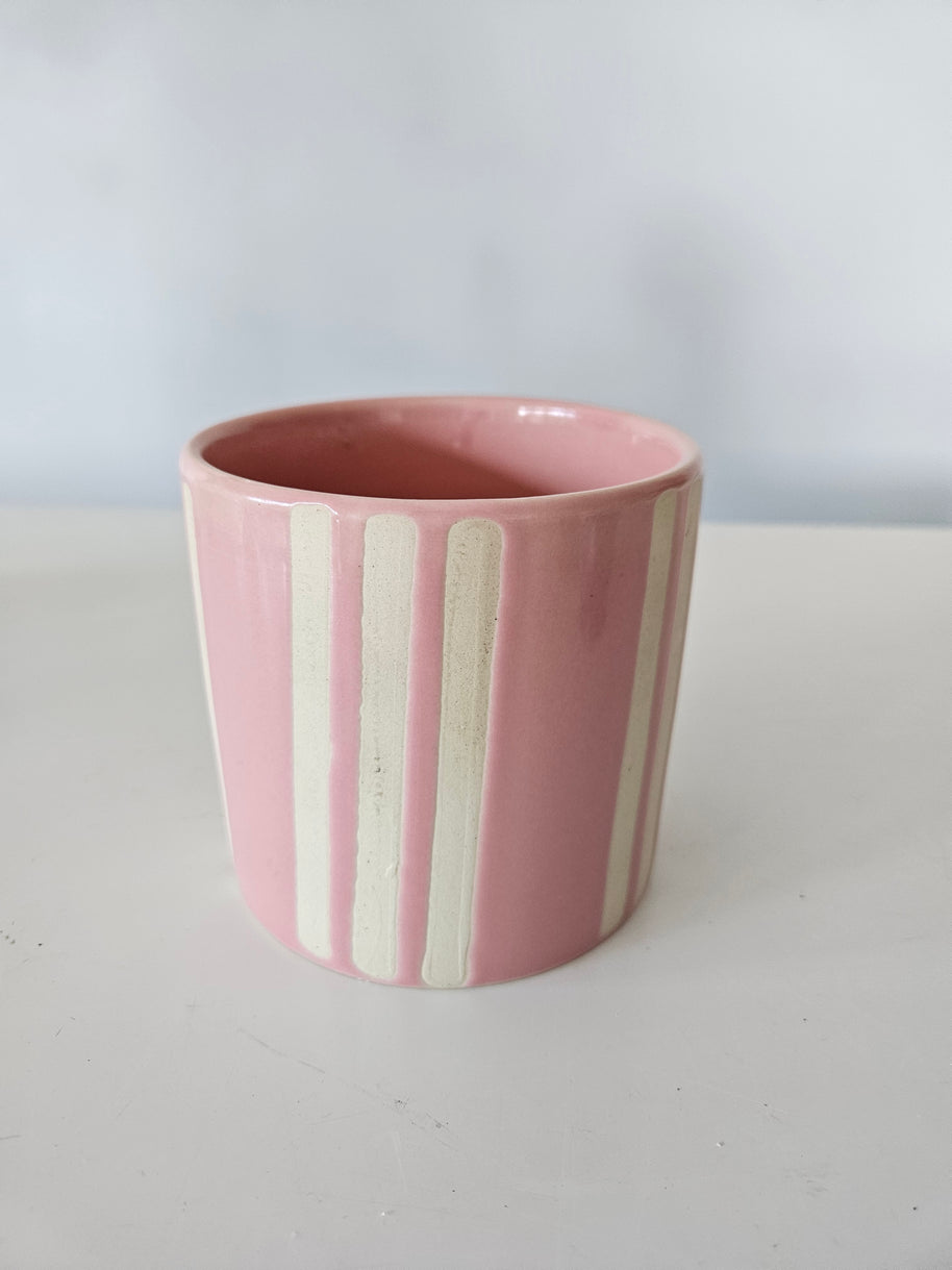 Pink and white ceramic striped pot on a white background