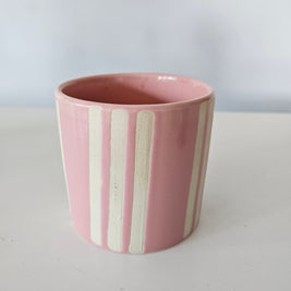 Pink and white ceramic striped pot on a white background