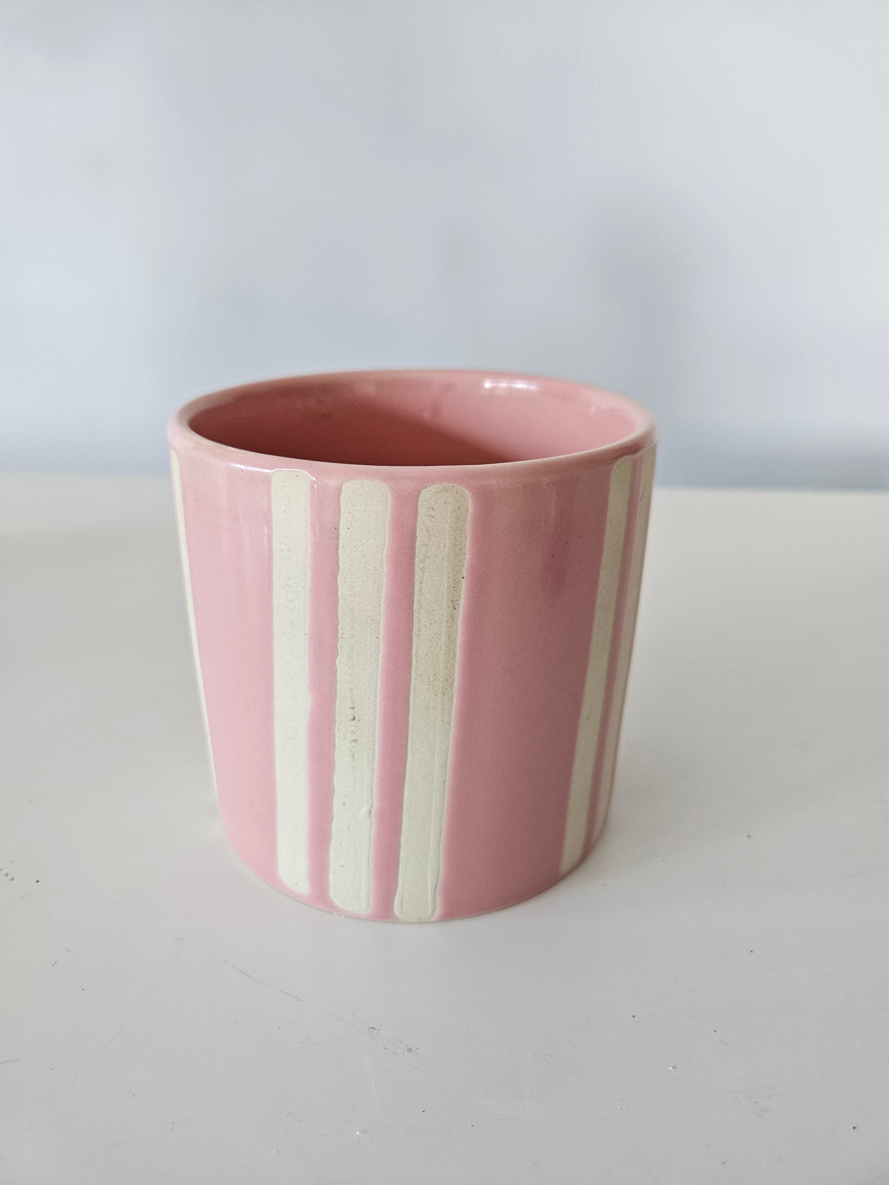 Pink and white ceramic striped pot on a white background