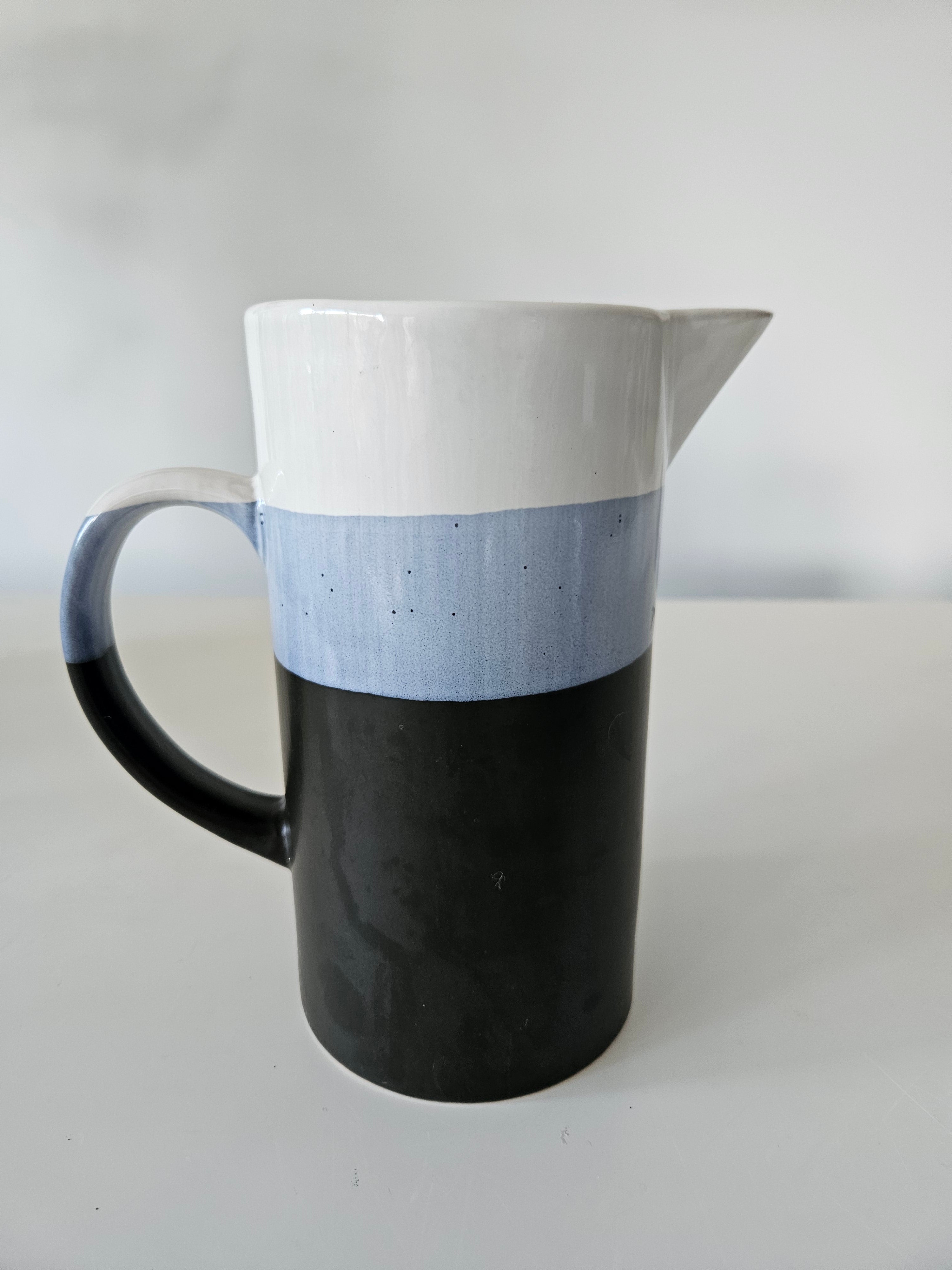 Black and white ceramic jug on a light grey background