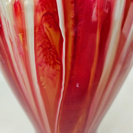 Close-up of damage on a red and white vase with swirling patterns.