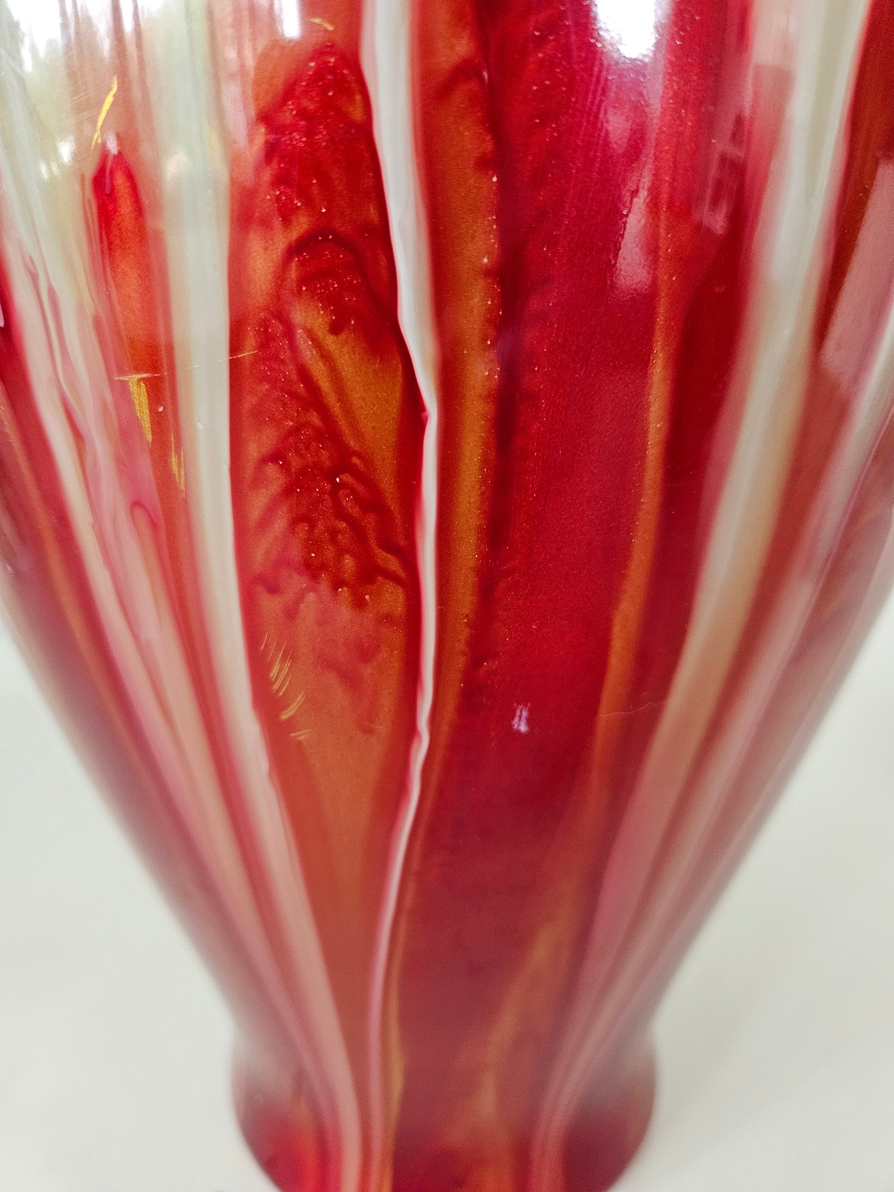 Close-up of damage on a red and white vase with swirling patterns.
