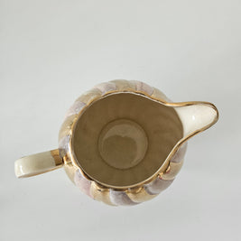 Top down view of a gold and purple ceramic teapot on a white background