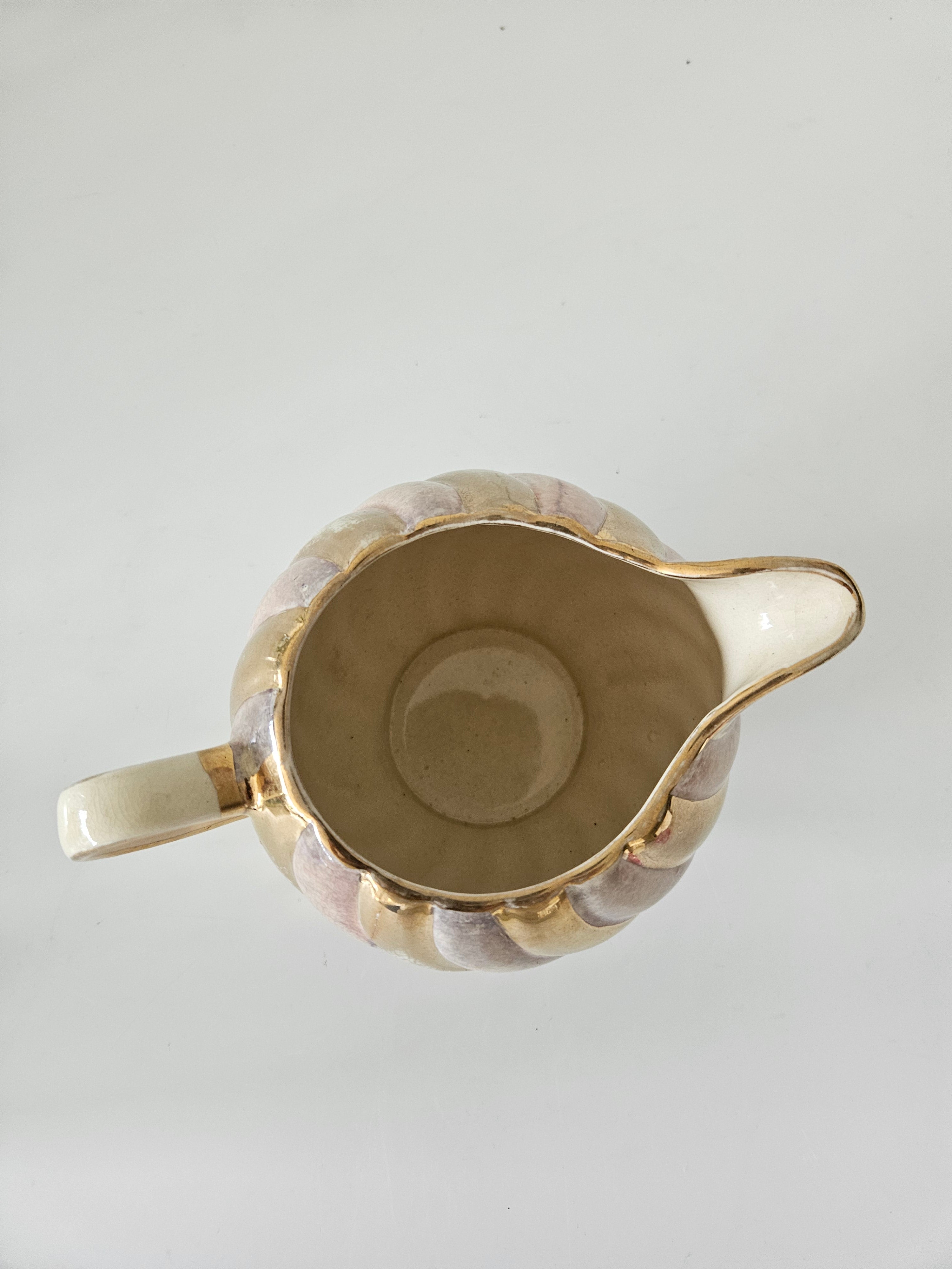 Top down view of a gold and purple ceramic teapot on a white background