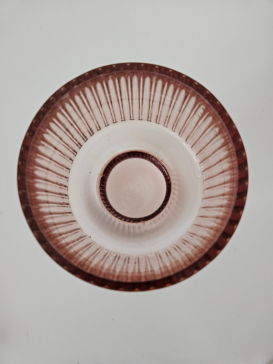 Top down view of a peach pink glass vase on a white background