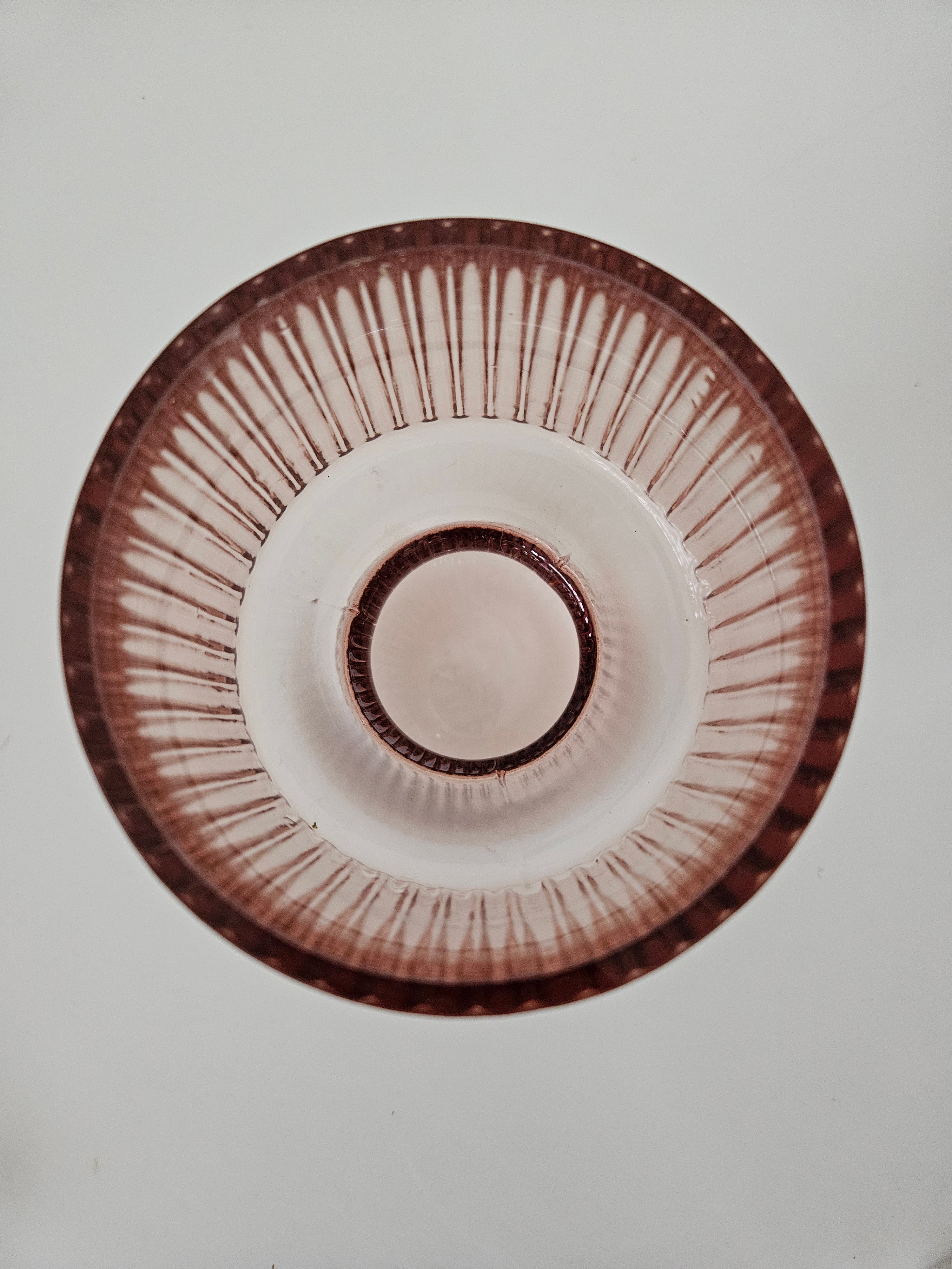 Top down view of a peach pink glass vase on a white background