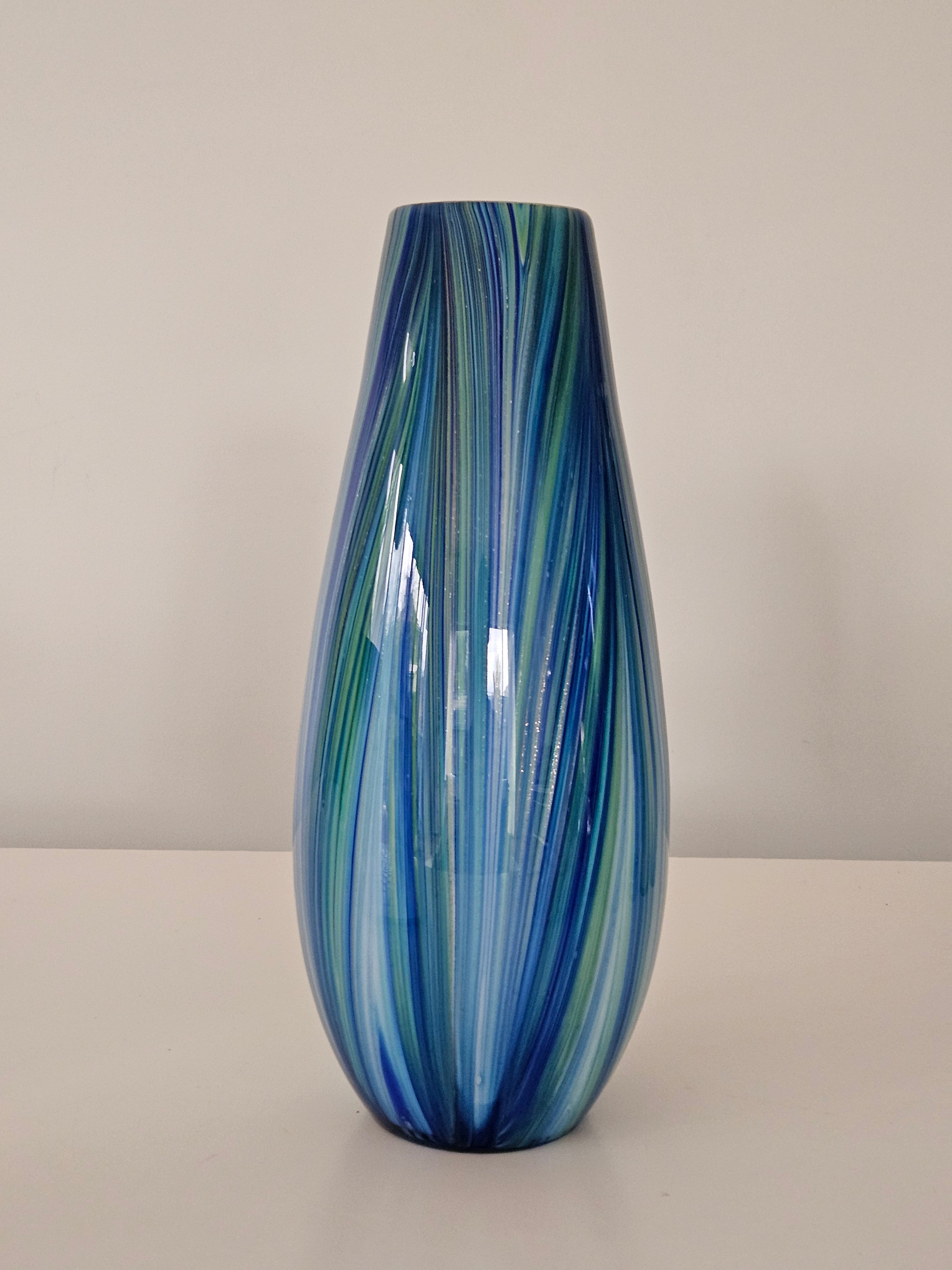 Glass vase with blue and green swirl pattern on a plain background