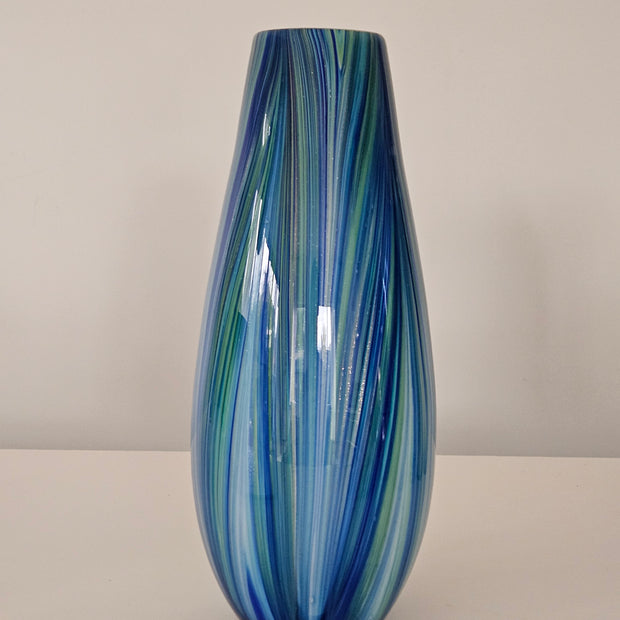 Glass vase with blue and green swirl pattern on a plain background