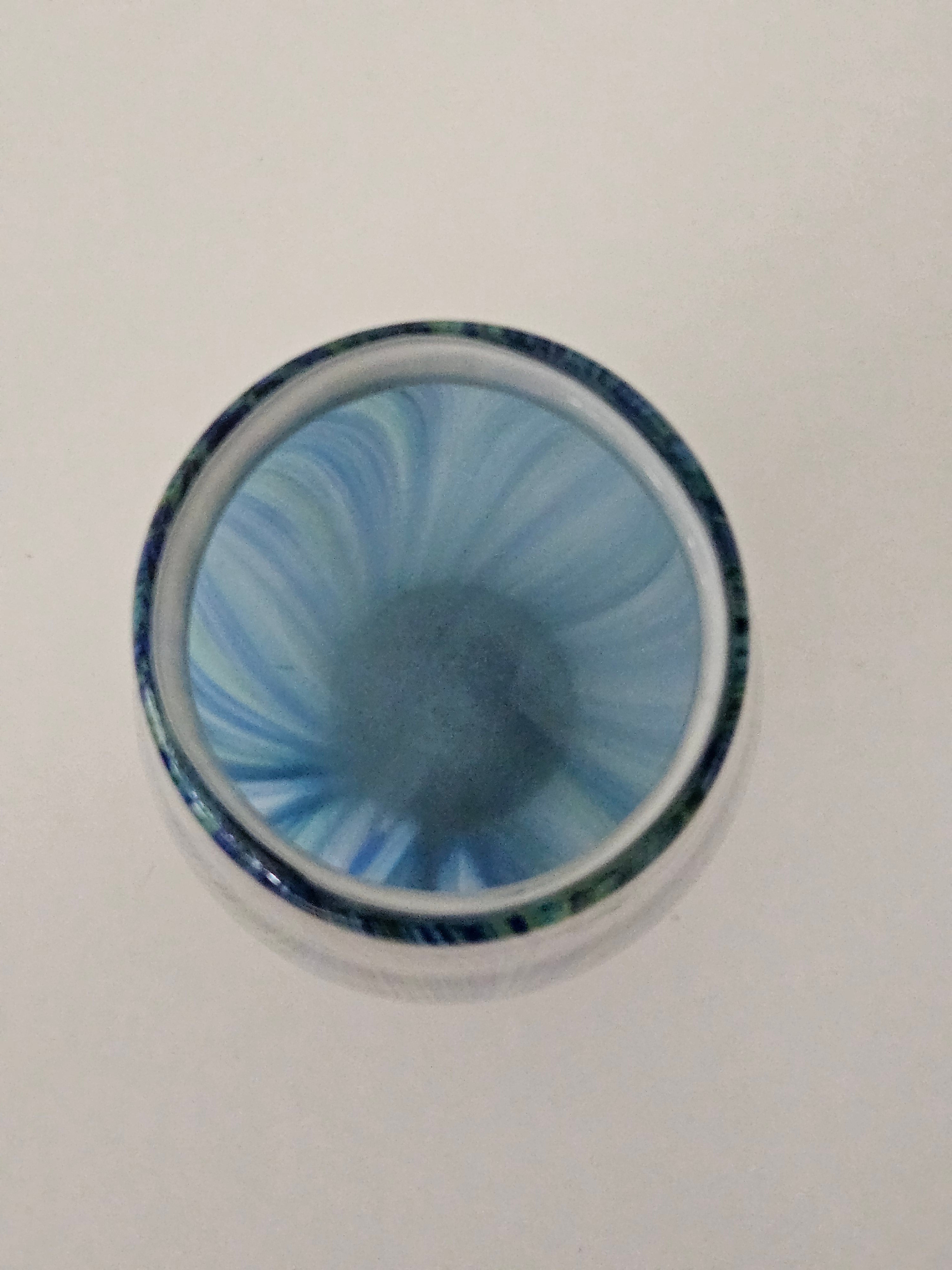 Top down view of a blue and green glass vase on a white background