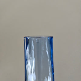 Close up of a small chip on a blue glass vase