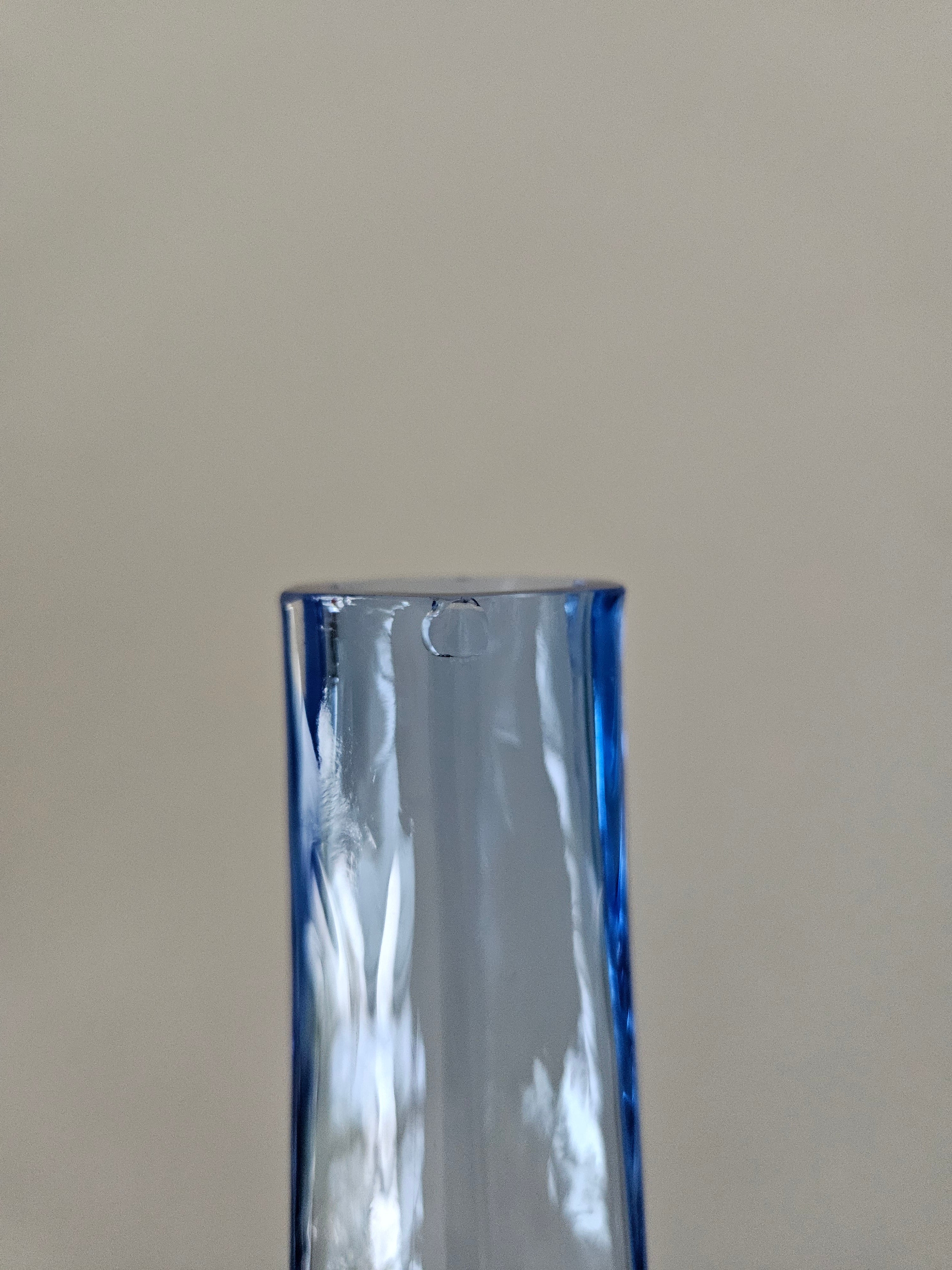 Close up of a small chip on a blue glass vase