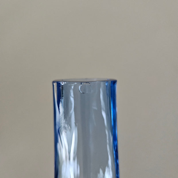 Close up of a small chip on a blue glass vase
